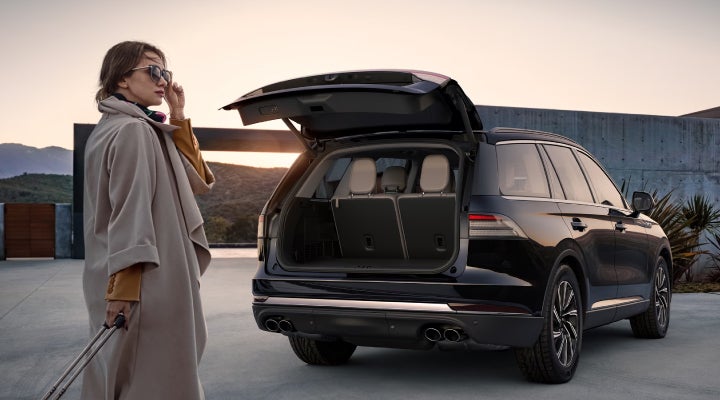 A woman approaches a 2026 Lincoln Aviator® SUV with its rear liftgate open. | Lincoln of Troy in Troy MI
