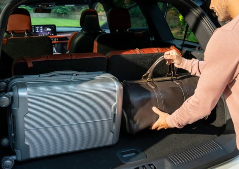 A man loads luggage into the rear of a 2026 Lincoln Aviator® SUV through the opened rear liftgate. | Lincoln of Troy in Troy MI