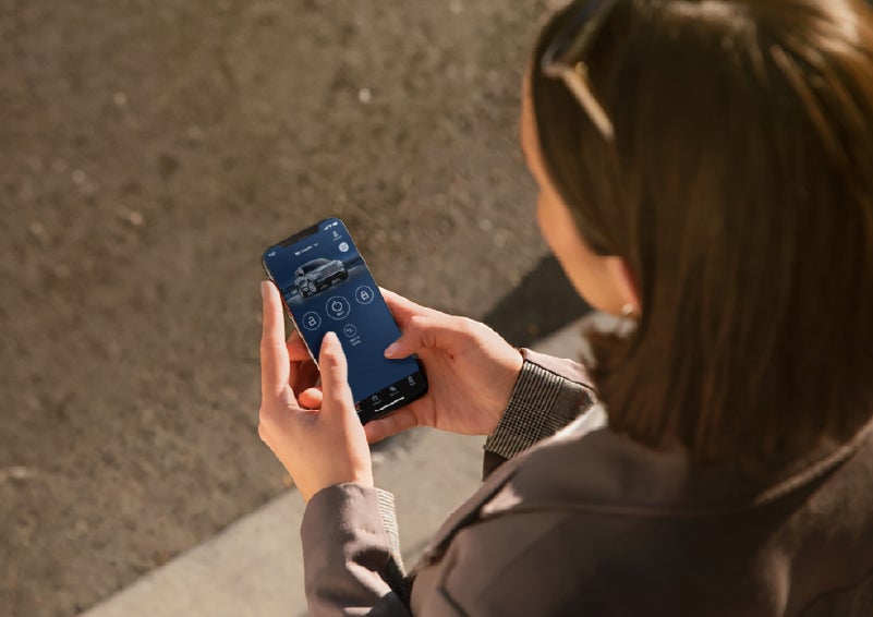 A person is shown interacting with a smartphone to connect to a Lincoln vehicle via the Lincoln Way® app. | Lincoln of Troy in Troy MI