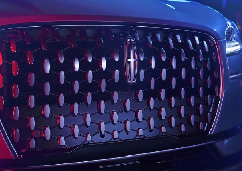 The grille of a 2025 Lincoln Corsair® SUV reflects neon light at night. | Lincoln of Troy in Troy MI