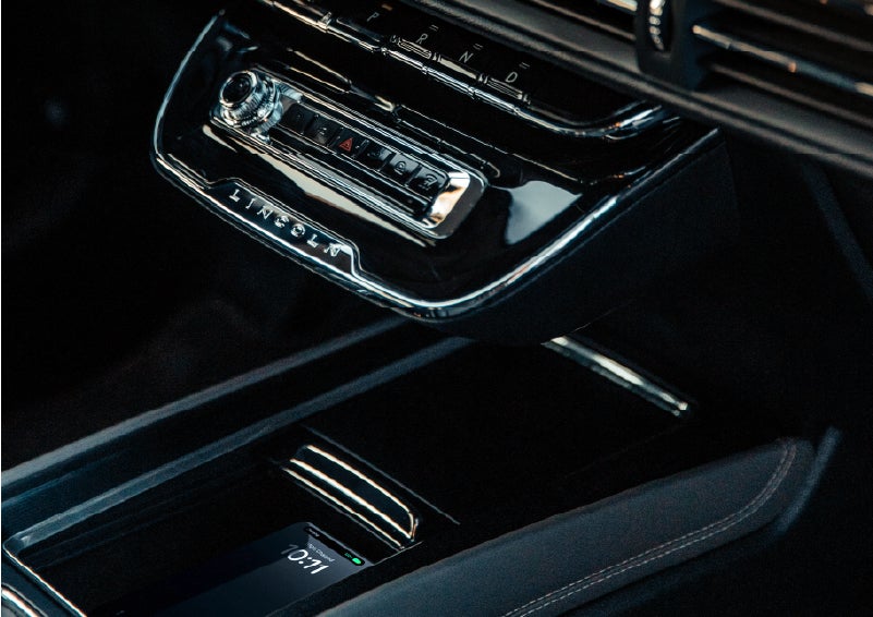 A smartphone rests on the available wireless charging pad in the front center console cubby. | Lincoln of Troy in Troy MI