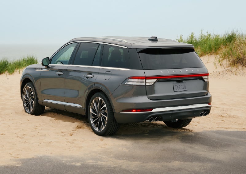 A 2027 Lincoln Aviator® SUV is parked next to sand dunes. | Lincoln of Troy in Troy MI