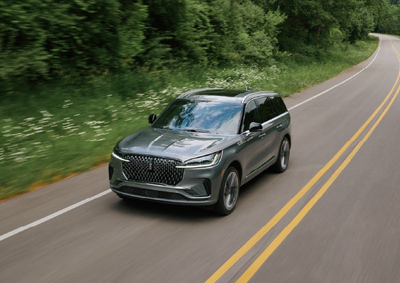 A 2027 Lincoln Aviator® SUV is being driven down a road. | Lincoln of Troy in Troy MI