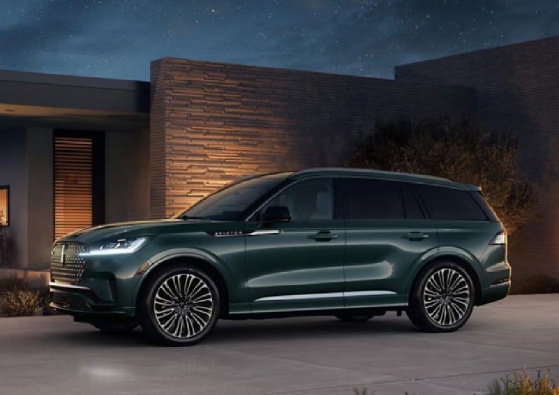 A green 2027 Lincoln Aviator® SUV is parked outside a contemporary home. | Lincoln of Troy in Troy MI