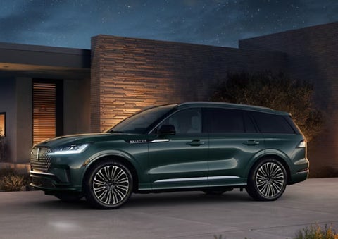A green 2027 Lincoln Aviator® SUV is parked outside a contemporary home. | Lincoln of Troy in Troy MI