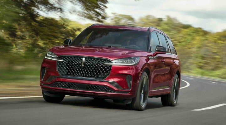 A 2027 Lincoln Aviator® SUV is being driven on a country road | Lincoln of Troy in Troy MI