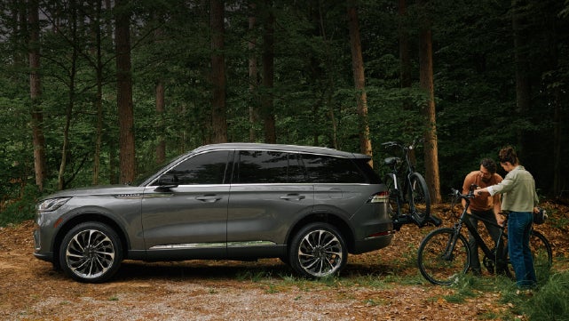 A father and son load e-bikes on a bike rack attached to a 2027 Lincoln Aviator® SUV. | Lincoln of Troy in Troy MI