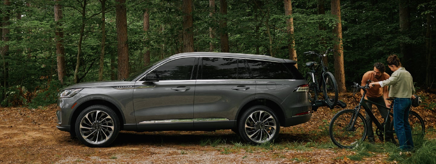A father and son load e-bikes on a bike rack attached to a 2027 Lincoln Aviator® SUV. | Lincoln of Troy in Troy MI