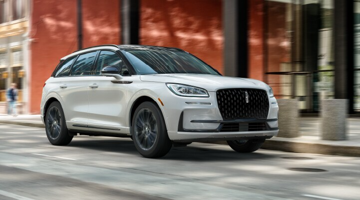 A white 2025 Lincoln Corsair SUV with the Jet Appearance Package is being driven through a city.