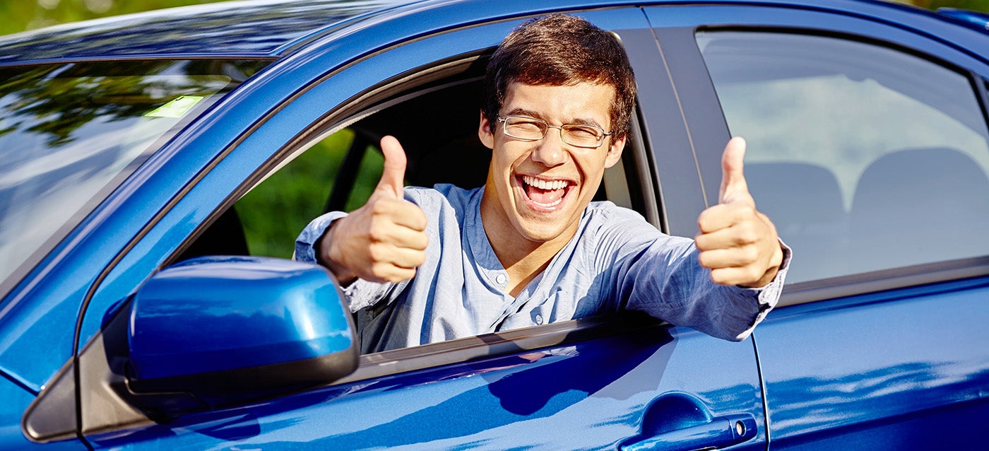 A person is leaning out of the open window with both hands raised in a thumbs-up gesture