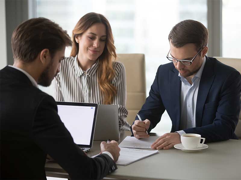 People reviewing and signing documents during a business meeting at a conference table
