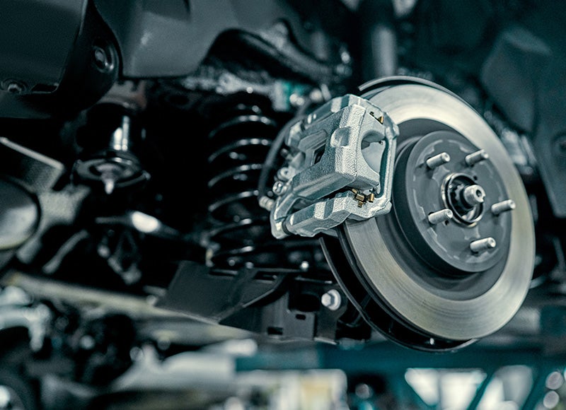 Close-up of a car's disc brake system, showing the caliper, rotor, and part of the suspension